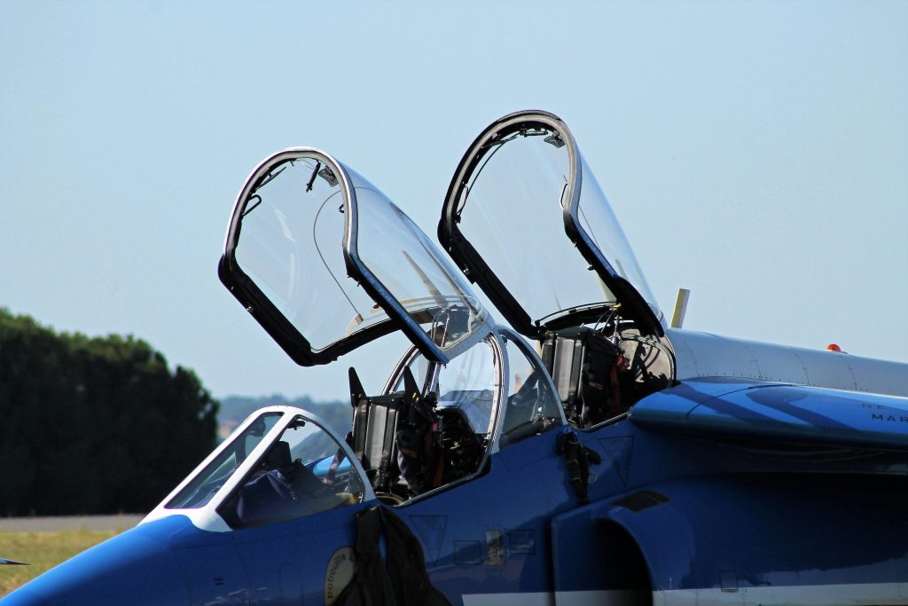 Close-up of an open jet cockpit on a runway, showcasing intricate details.
